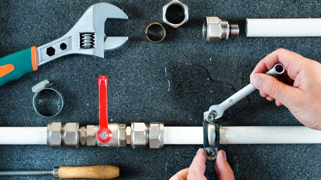 Plumber repairing a pipe valve with an adjustable wrench in Gibsonton