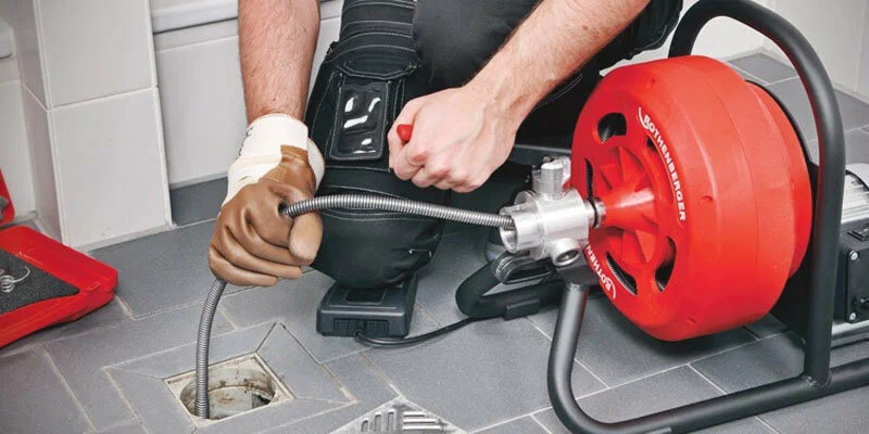 Plumber using a drain-cleaning machine in Gibsonton