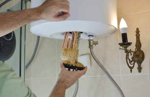 Technician removing mineral buildup from a water heater in Gibsonton